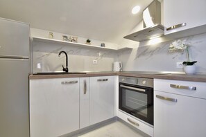 A modern kitchen with white cabinetry, a built-in oven, and a stainless steel faucet.