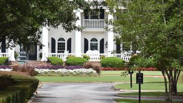 A white building with a white porch, arched windows, and a sign indicating a golf cart parking area.