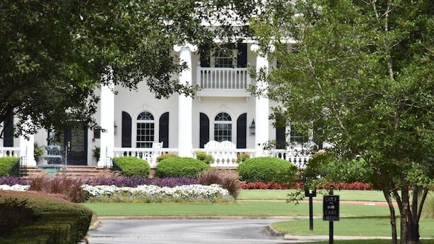 A white building with a white porch, arched windows, and a sign indicating a golf cart parking area.
