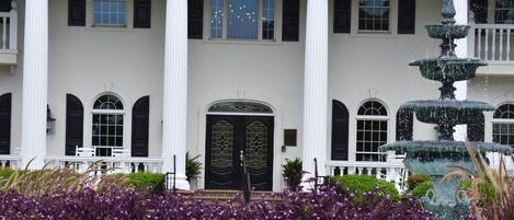 A stately building with a large entrance, numbered 380, flanked by white columns and a multi-tiered fountain.