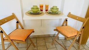 Een kleine eettafel met twee groene kommen en twee glaasjes op een witte tafelkleed.