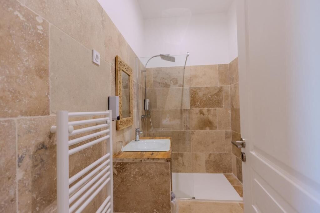 Une salle de bain avec une douche, un lavabo et un porte-serviettes.