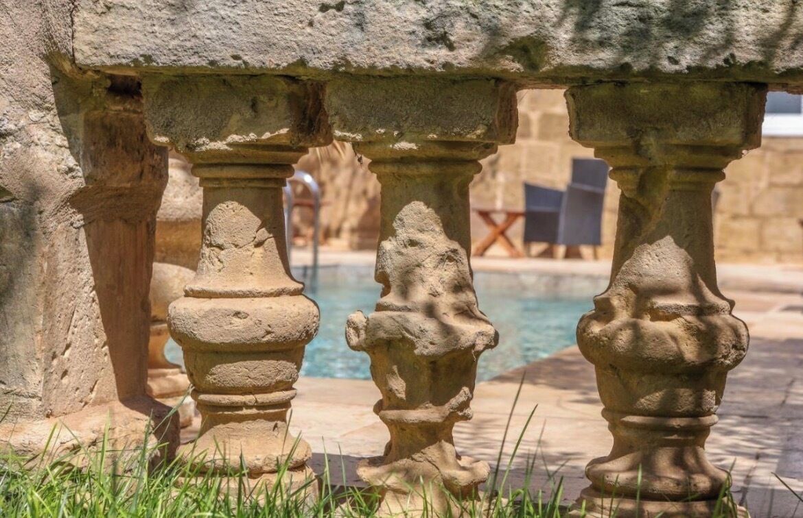 A stone balustrade with a pool in the background.