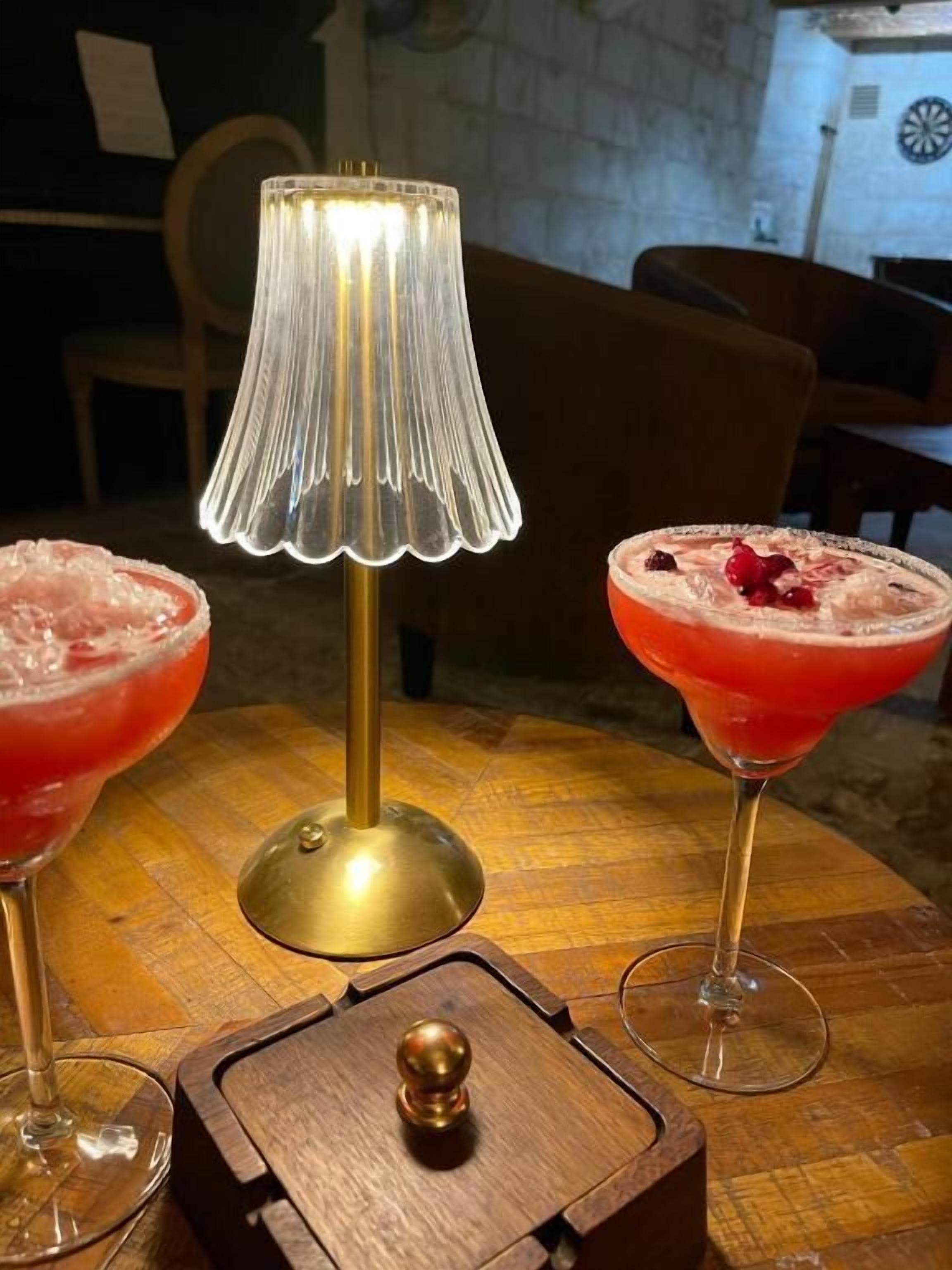 Une table avec deux boissons, une lampe et une boîte en bois.