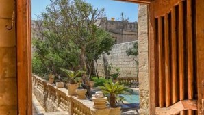 An open arched doorway leading to a courtyard with a pool, potted plants, and a stone wall. - Palazzo Pisani Malta Boutique & Spa (Zabbar)