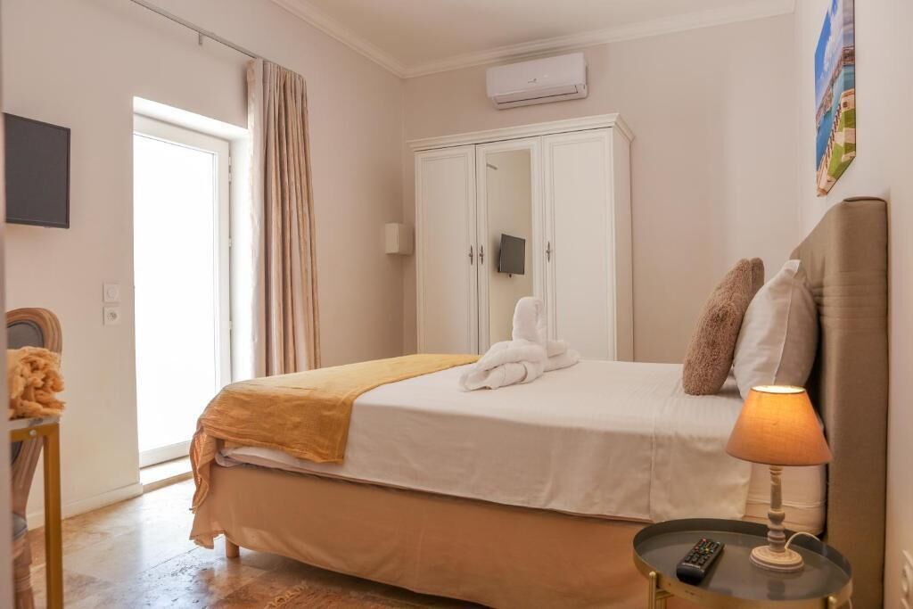 A bedroom with a bed, a wardrobe, a bedside table with a lamp, and a remote control.