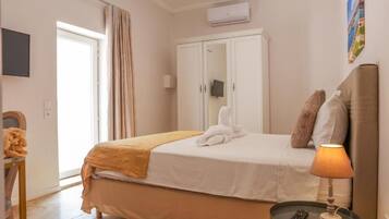 A bedroom with a bed, a wardrobe, a bedside table with a lamp, and a remote control.