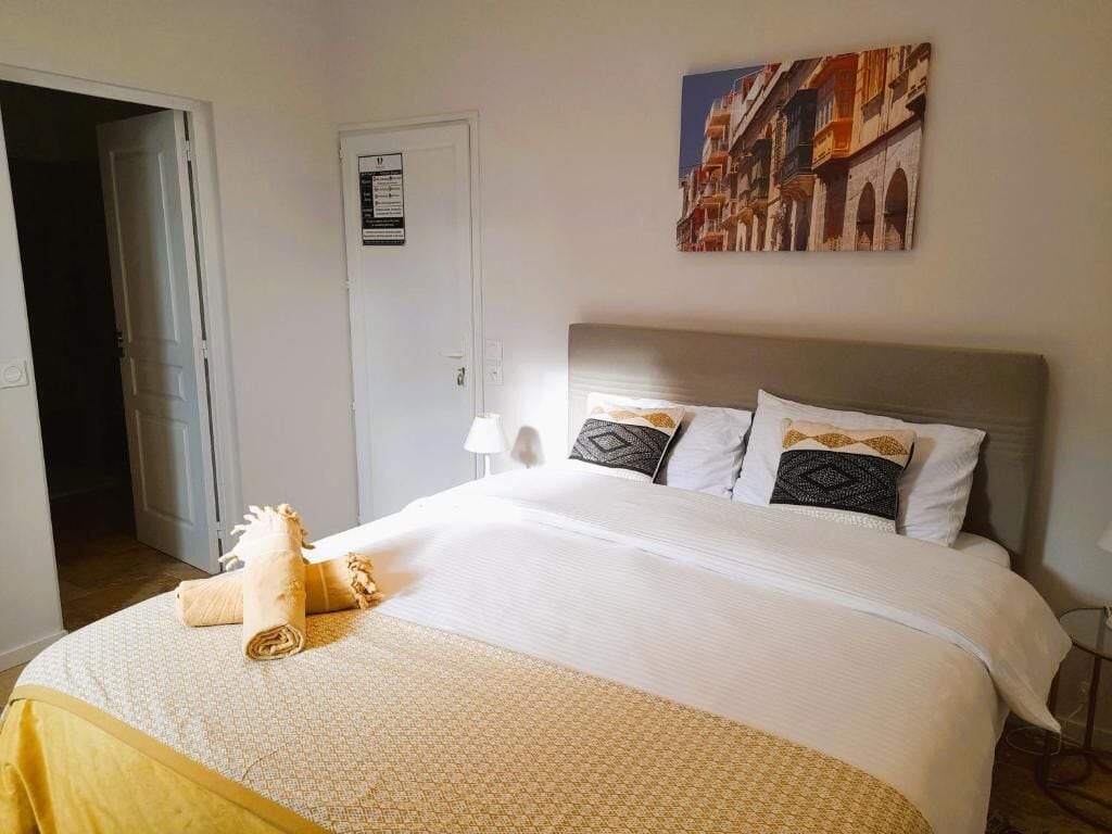 Ein Hotelzimmer mit Bett, Tür, einem Wandbild und einem Handtuch auf dem Bett.
