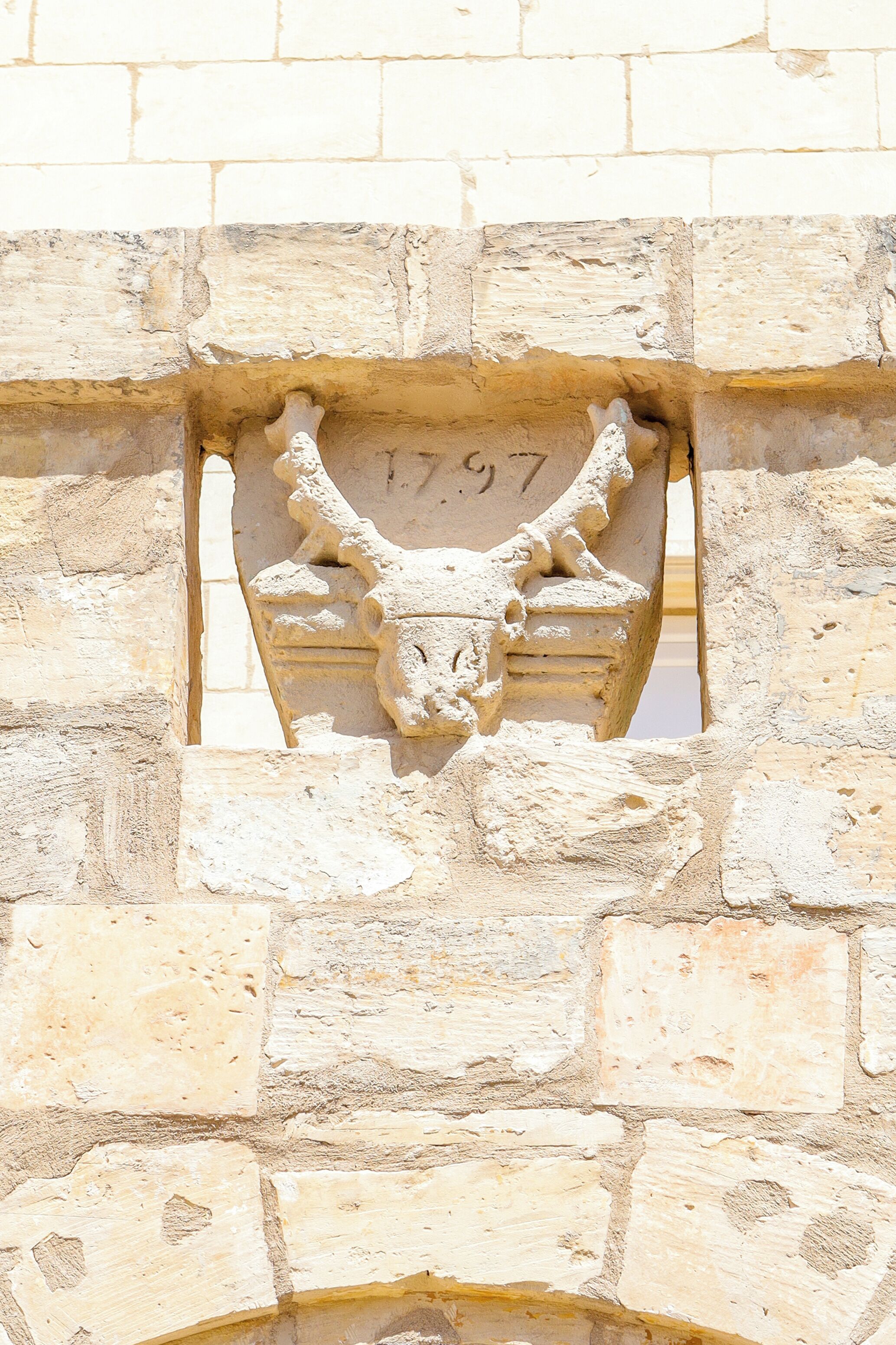 A stone wall with a carved bull's head and the number '97' on it.