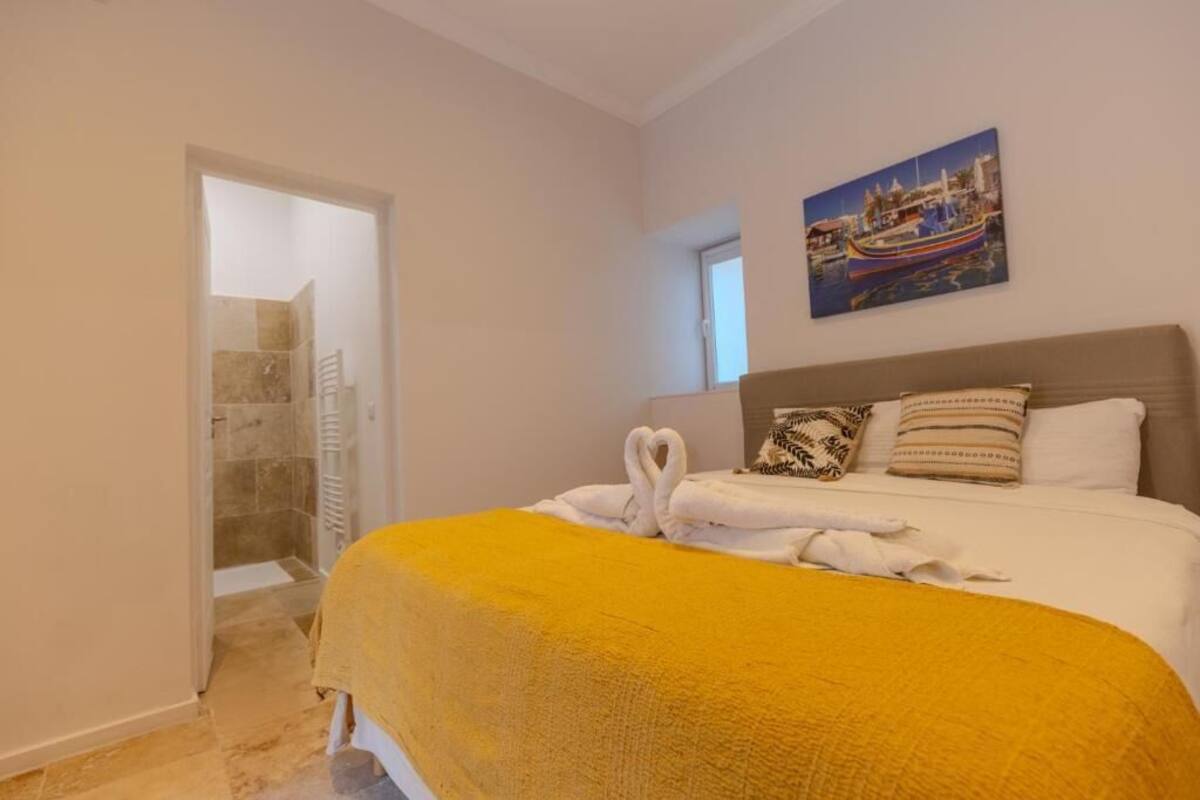 A bedroom with a bed, a painting, and a shower area.