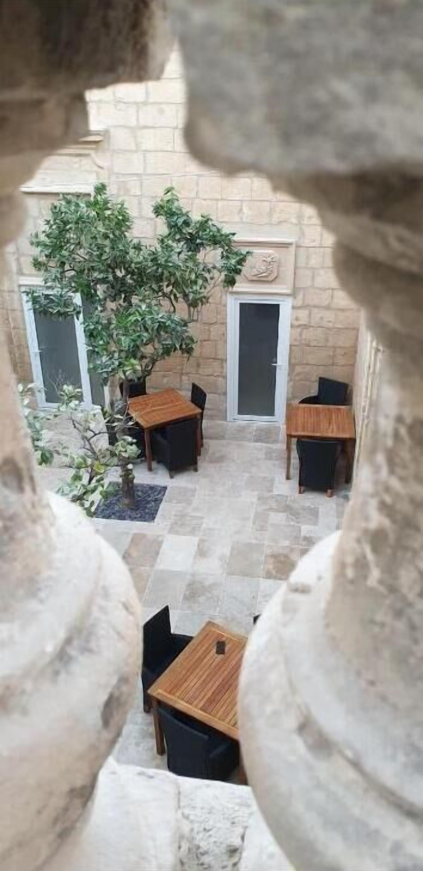 An outdoor patio with stone flooring, a wooden table, and chairs.
