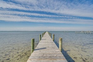 Une jetée en bois s’étendant sur des eaux calmes, sous un ciel dégagé.