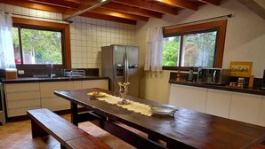 Une cuisine avec une table en bois, un banc et un réfrigérateur.