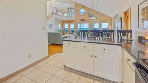 Une cuisine spacieuse dotée d’un grand îlot central, de touches de bois et offrant une vue sur l’extérieur.
