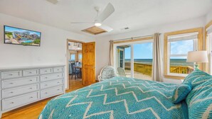 Une chambre avec un lit, une commode, un ventilateur de plafond et une vue sur la plage.