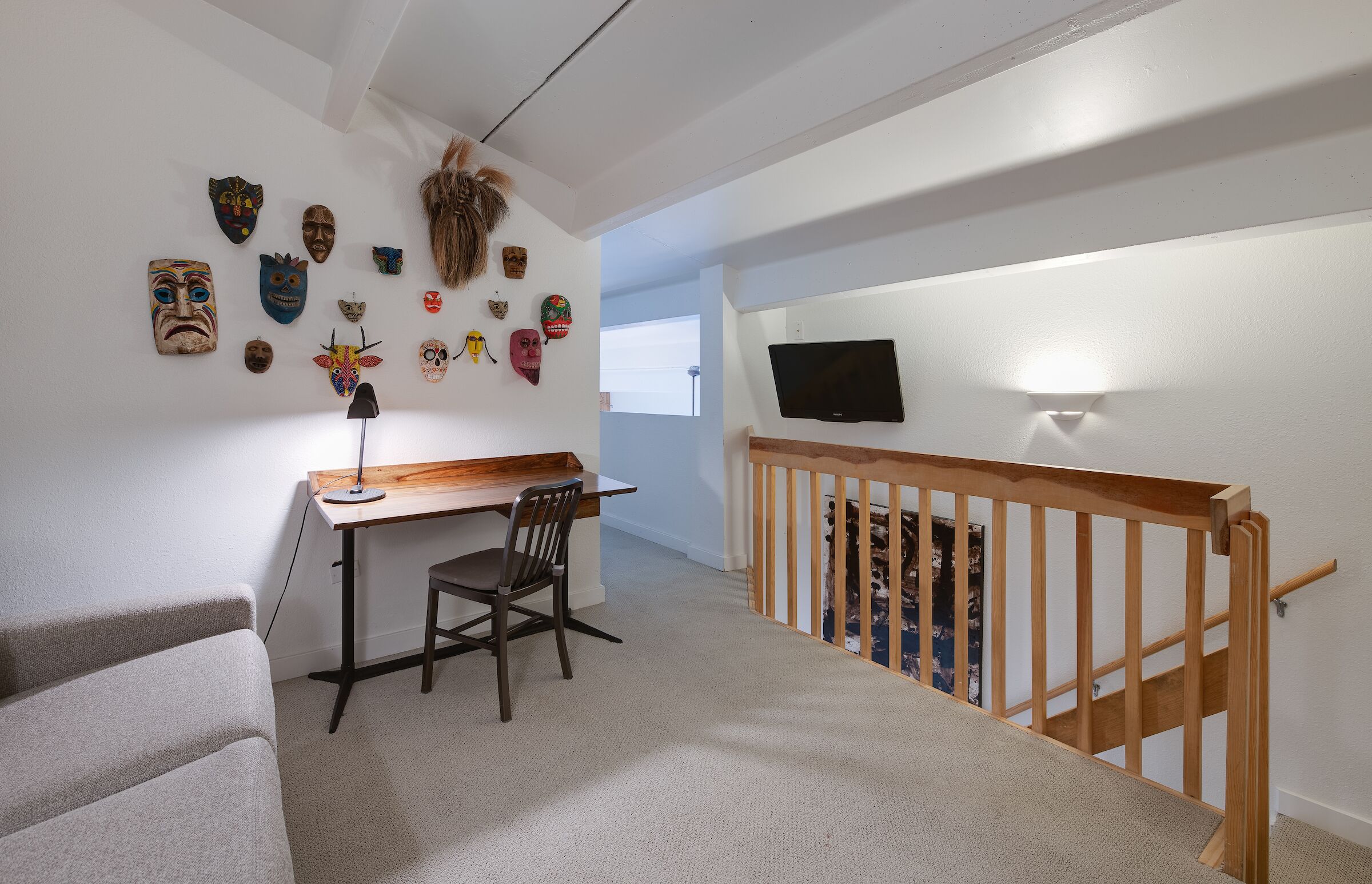 Una habitación con escritorio, silla y televisor montado en la pared.