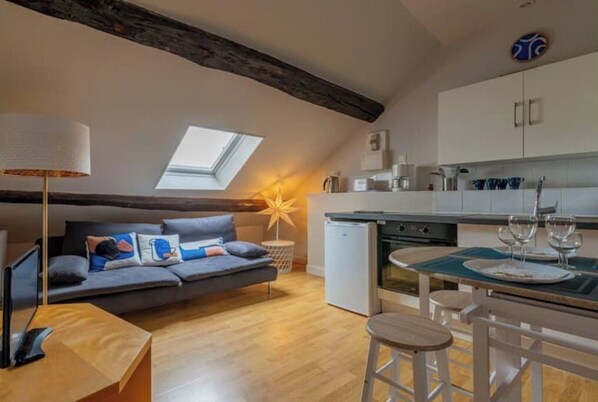 A cozy loft-style living space with a dining area, a kitchenette, and a large skylight.