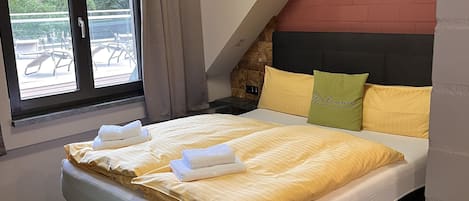 Un dormitorio moderno con una cama grande, una ventana con cortinas y una pared de ladrillo decorativa.