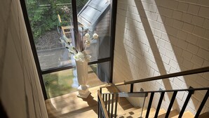 A wooden staircase with a white brick wall and a window overlooking a garden. - Zweirad Hotel Lenne (Schwerin)