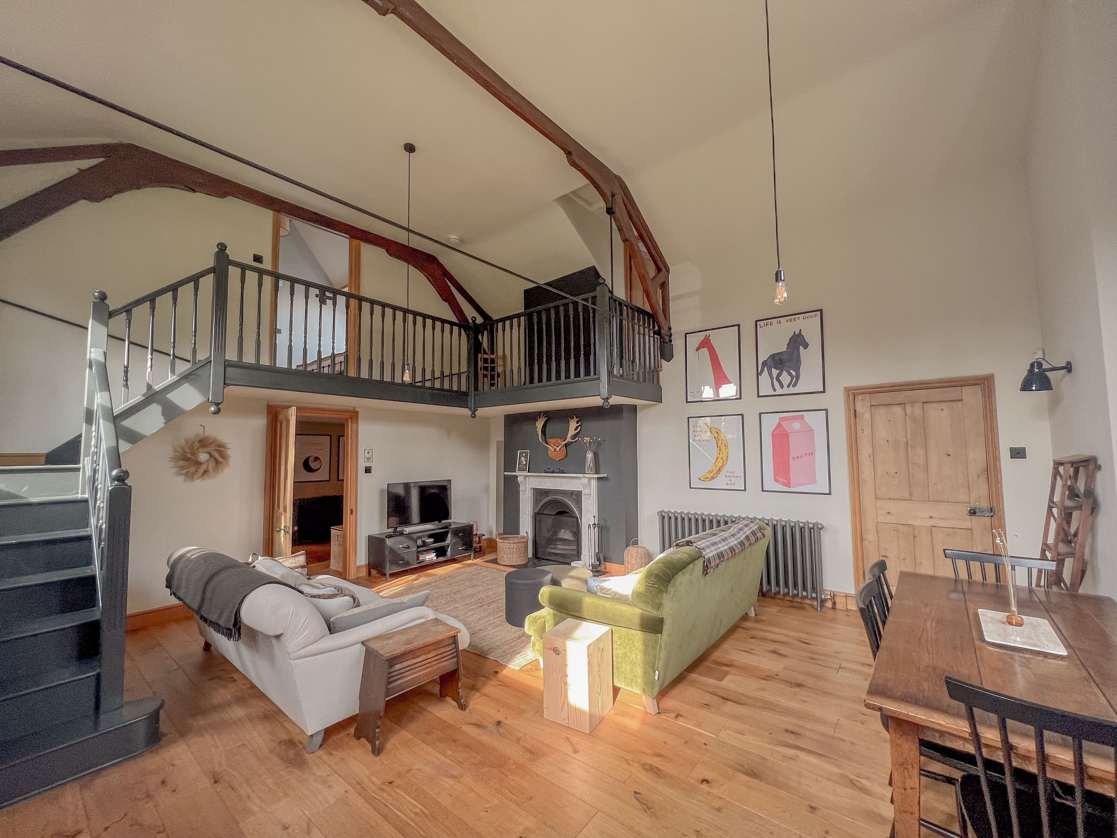 A spacious living area with a staircase, a fireplace, and a dining table.