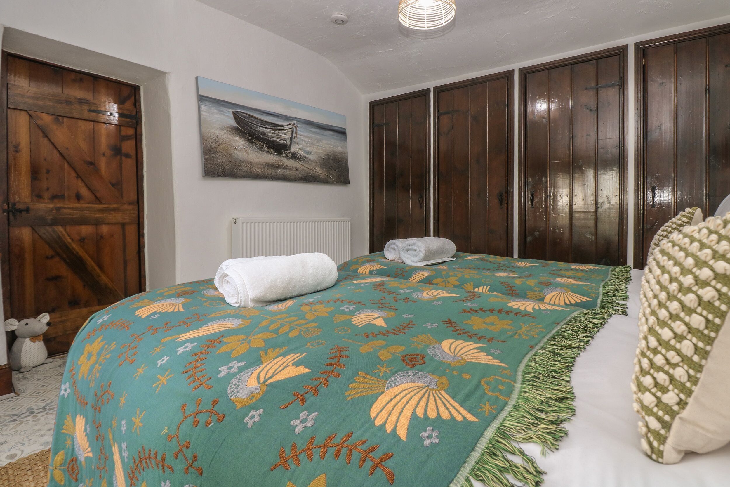A bedroom with a bed, a wooden wardrobe, a radiator, and a painting on the wall.