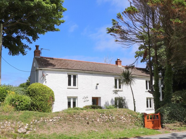 A white two-story house with a red roof, a small garden, and a wooden gate. - Myrtle Cottage (Hayle)