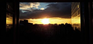 A sunset view through a window with a cityscape in the background.
