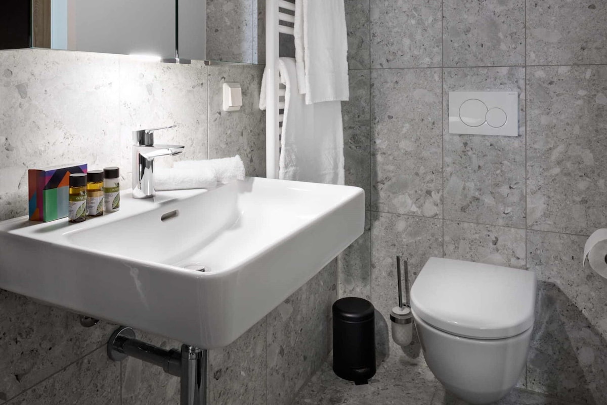 A modern bathroom with a white sink, a toilet, and a towel rack.