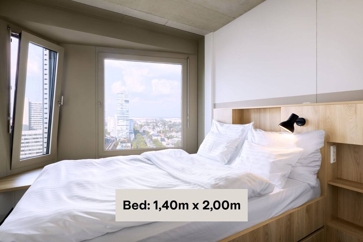 A bed measuring 1.40m x 2.00m in a modern room with a city view.