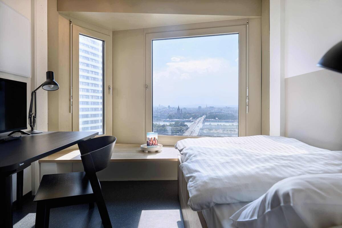 A hotel room with a desk, chair, and bed.