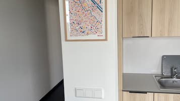 A modern kitchen with wooden cabinets, a stainless steel sink, and a framed city map on the wall.