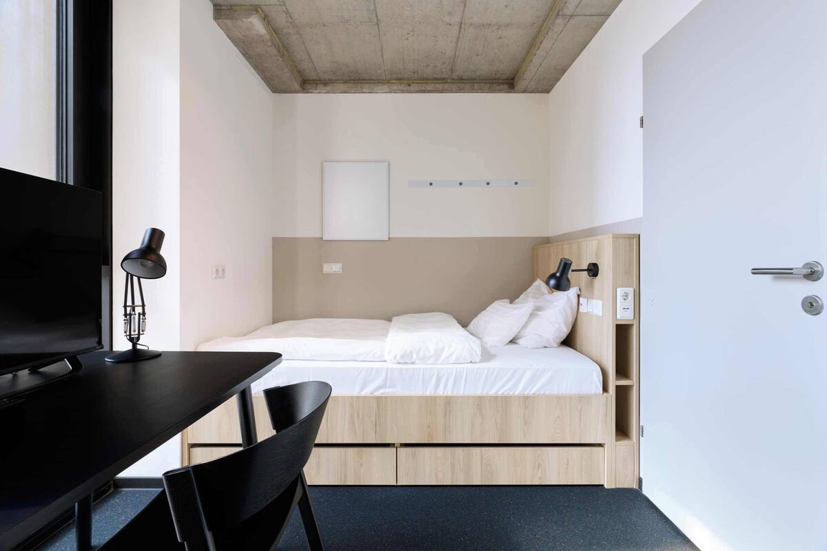 A compact bedroom with a bed, a desk, and a chair.