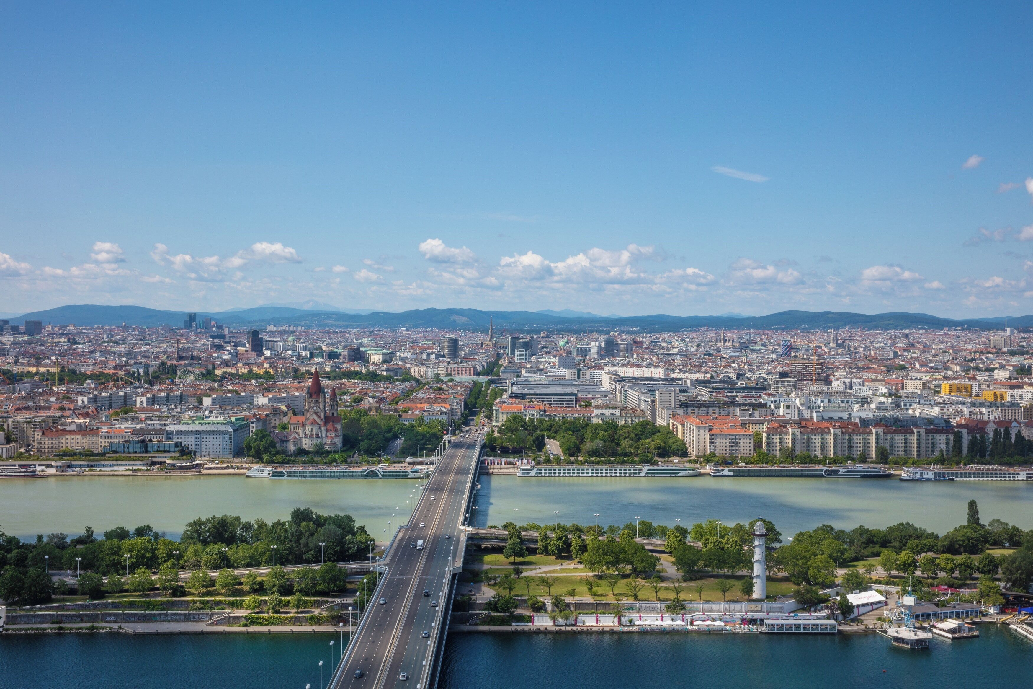 A cityscape with a prominent bridge spanning a river, surrounded by urban buildings and greenery.