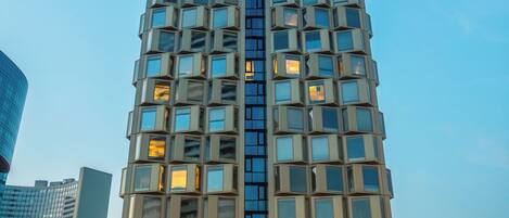 Un edificio alto y moderno con fachada de entramado y múltiples ventanas.