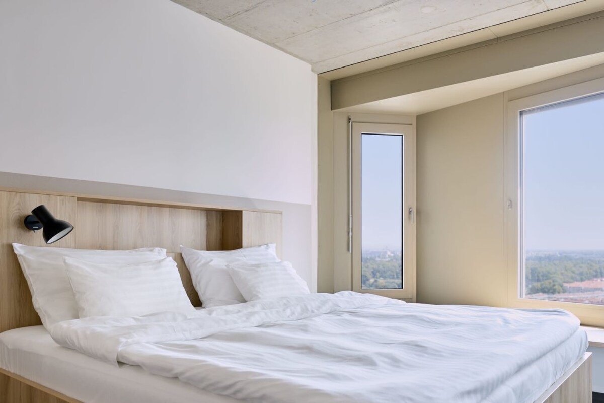 A modern bedroom with a bed measuring 1.80m x 2.00m, large windows, and a city view.