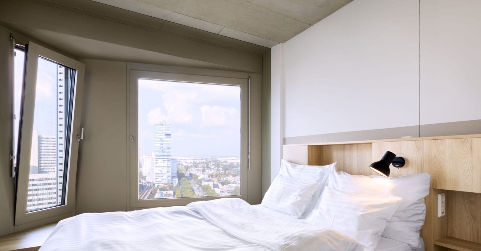 Un lit de 1,40 m x 2,00 m dans une chambre moderne avec vue sur la ville.