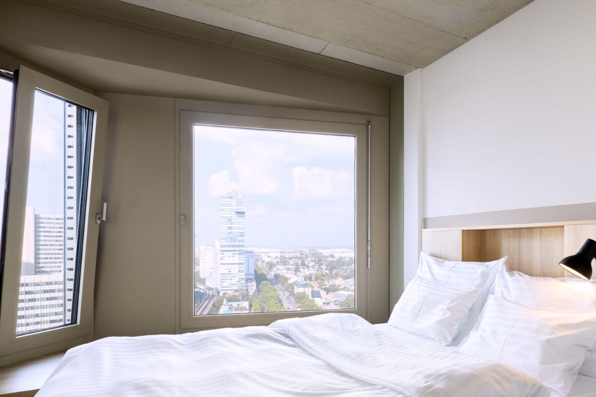A bed measuring 1.40m x 2.00m in a modern room with a city view.