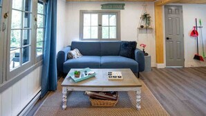 A cozy room with a blue sofa, a wooden coffee table, and a 'Beach House' sign on the wall. - Hydrus cozy 2 bedroom cottage (Kawartha Lakes)