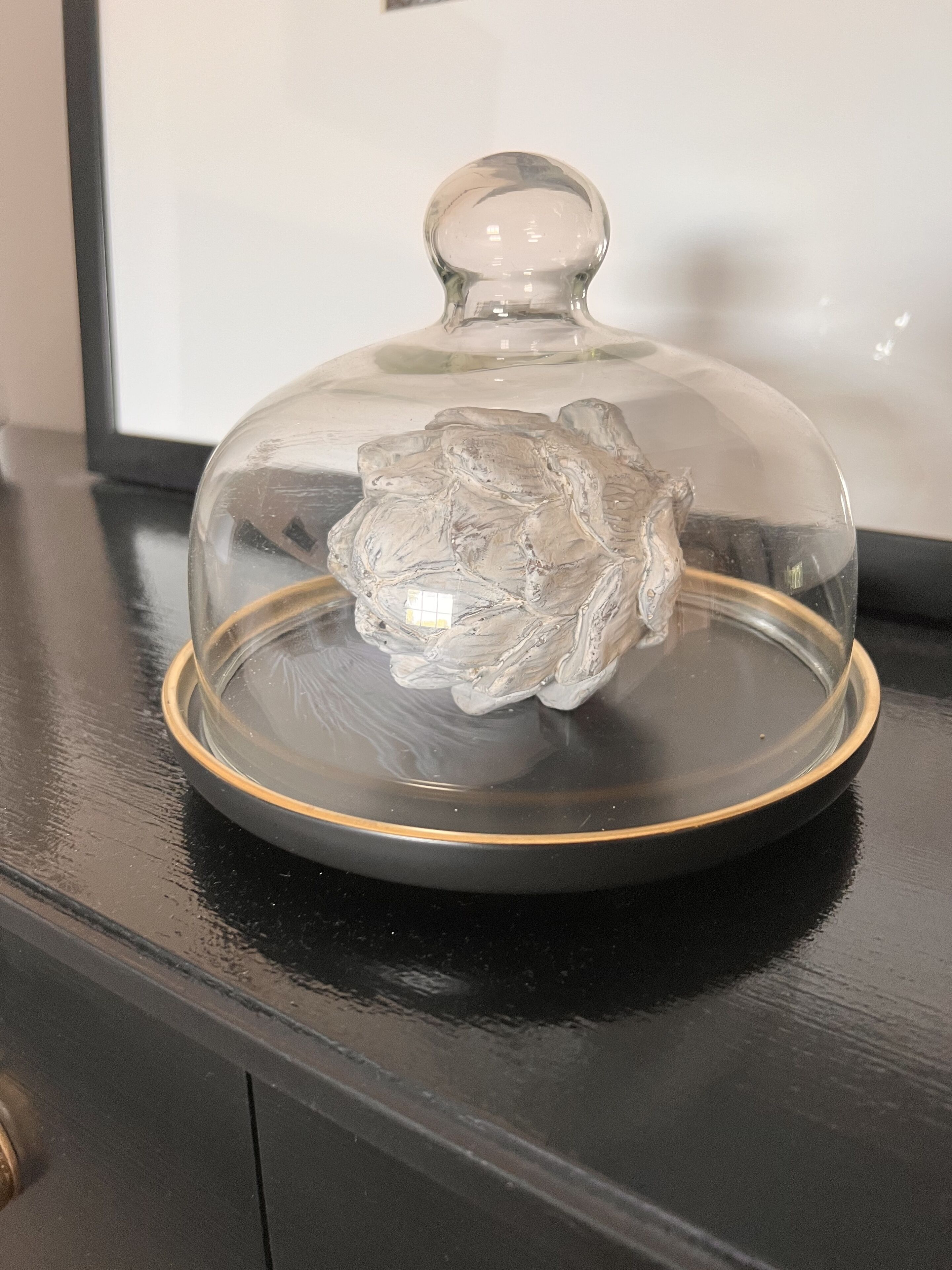 A clear glass dome with a textured base on a black surface.