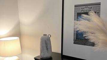 A modern room with a black dresser, a framed picture on the wall, a lamp, and a decorative vase.