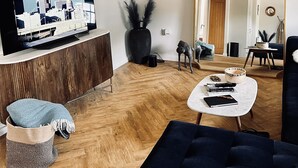 Una sala de estar moderna con un televisor de pantalla plana, un espejo grande y piso de madera.