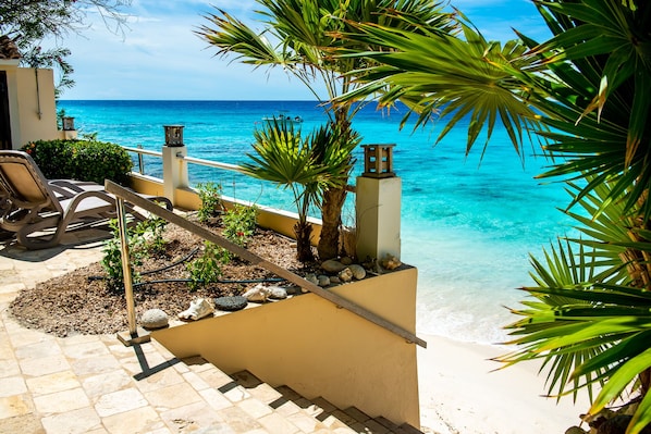 Ein Poolbereich mit freiem Blick auf den Ozean, einem Liegestuhl und einem kleinen Garten mit Steinen und Pflanzen.