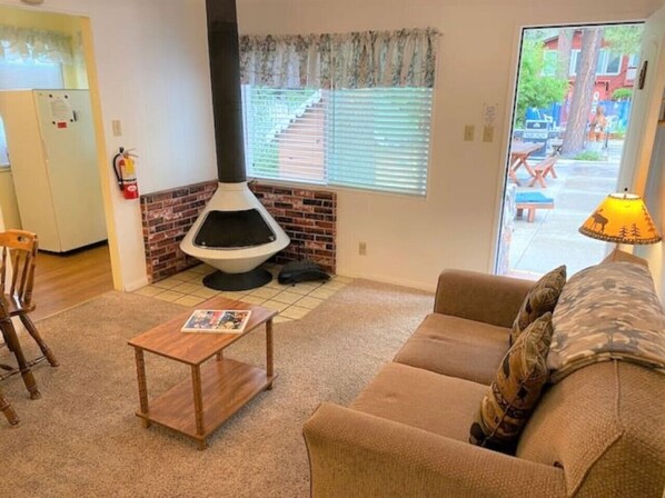 A living room with a sofa, a coffee table, a fireplace, and a view of the outside.