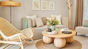 A living room with a sofa, a wicker chair, a round wooden coffee table, and a floor lamp. - Hotel Teranka (Formentera)