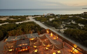 A beachfront resort with thatched-roof huts, outdoor seating, and a view of the sea. - Hotel Teranka (Formentera)