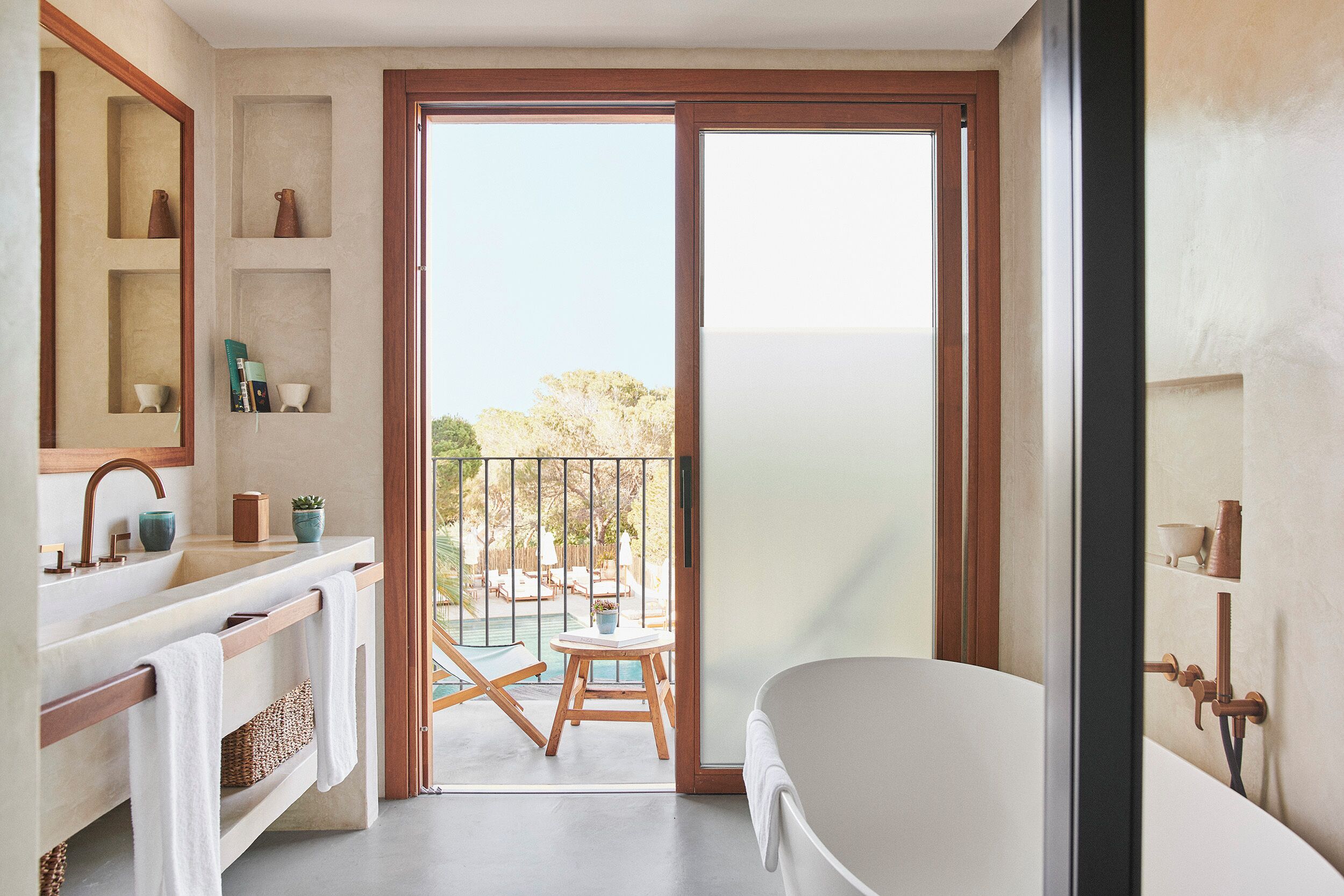 A modern bathroom with a bathtub, a sink with a mirror, and a shelf with decorative items.