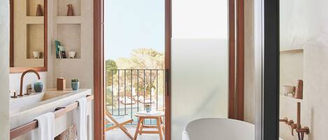 A modern bathroom with a bathtub, a sink with a mirror, and a shelf with decorative items.
