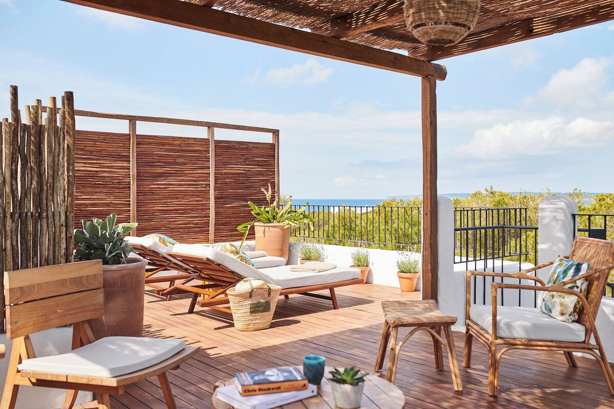 A wooden deck with lounge chairs, a table, and potted plants.