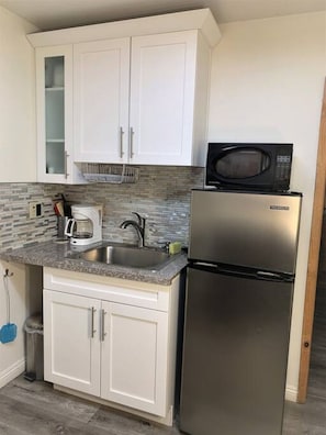 Efficient kitchen with a stainless steel refrigerator, granite countertop, and sink.