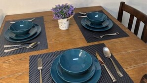 Une table à manger avec des assiettes bleues, des couverts en argent et une petite plante en pot.